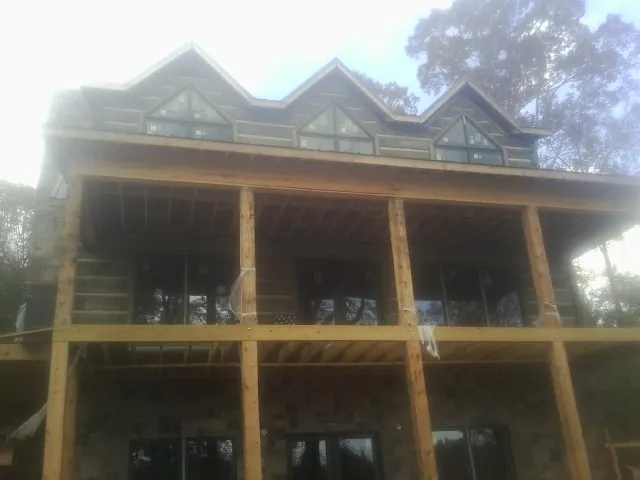 Dormers and porch framing on a large log home under construction — Roof Coating work by our crew in Hamer