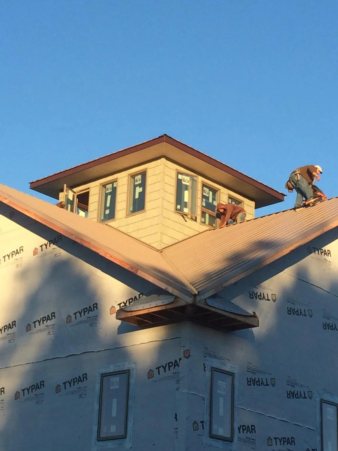 Roofers working around a rooftop cupola on a new metal roof at sunset — Roof Waterproofing in Hamer by Roofing Brothers